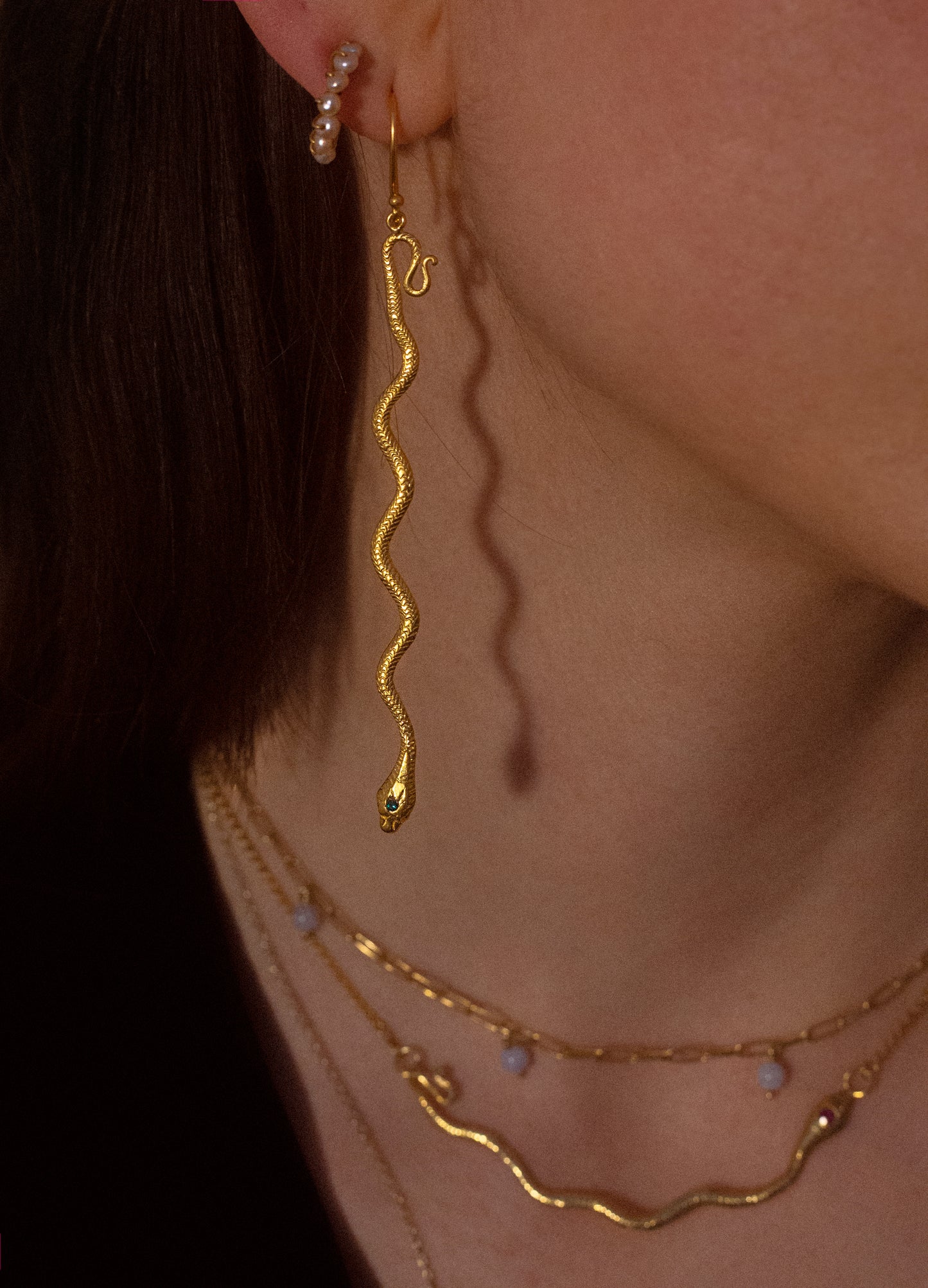 gold snake dangle earrings on model